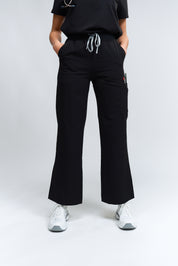 A person standing wearing high-waisted black wide leg scrub pants with an elastic waistband and antimicrobial fabric.