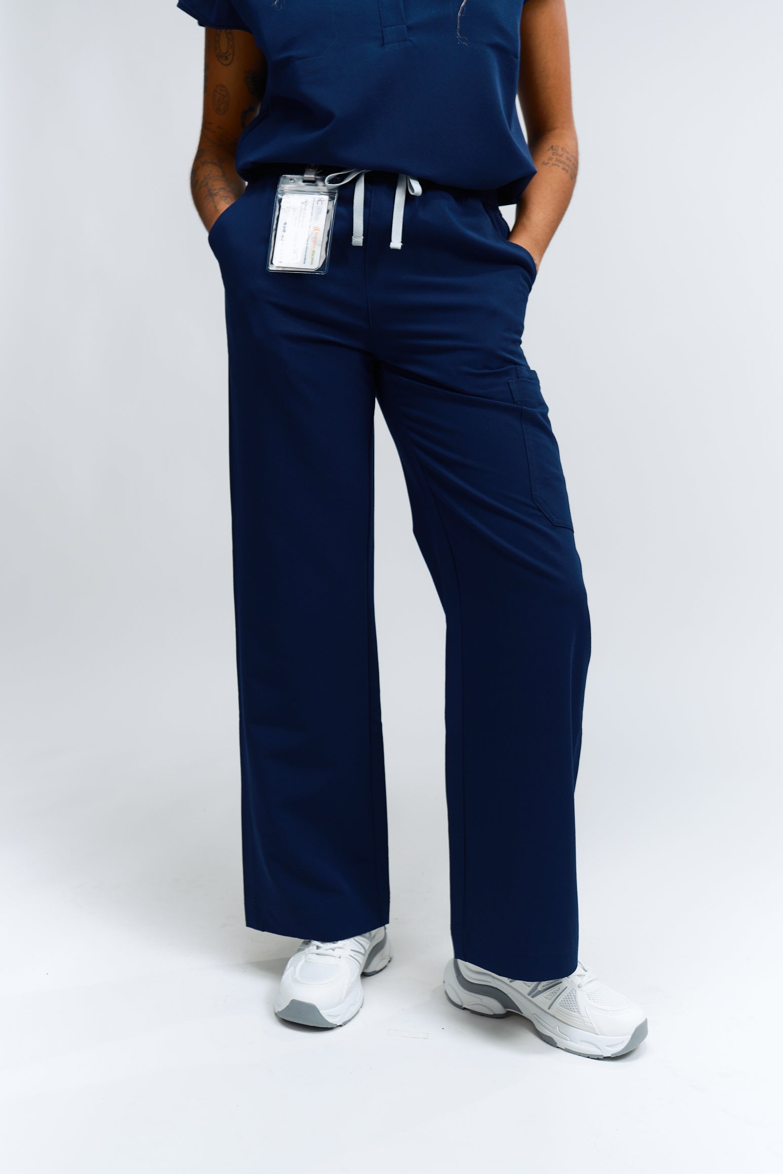 A person wearing navy wide leg scrub pants with an elastic waistband, standing against a white background.